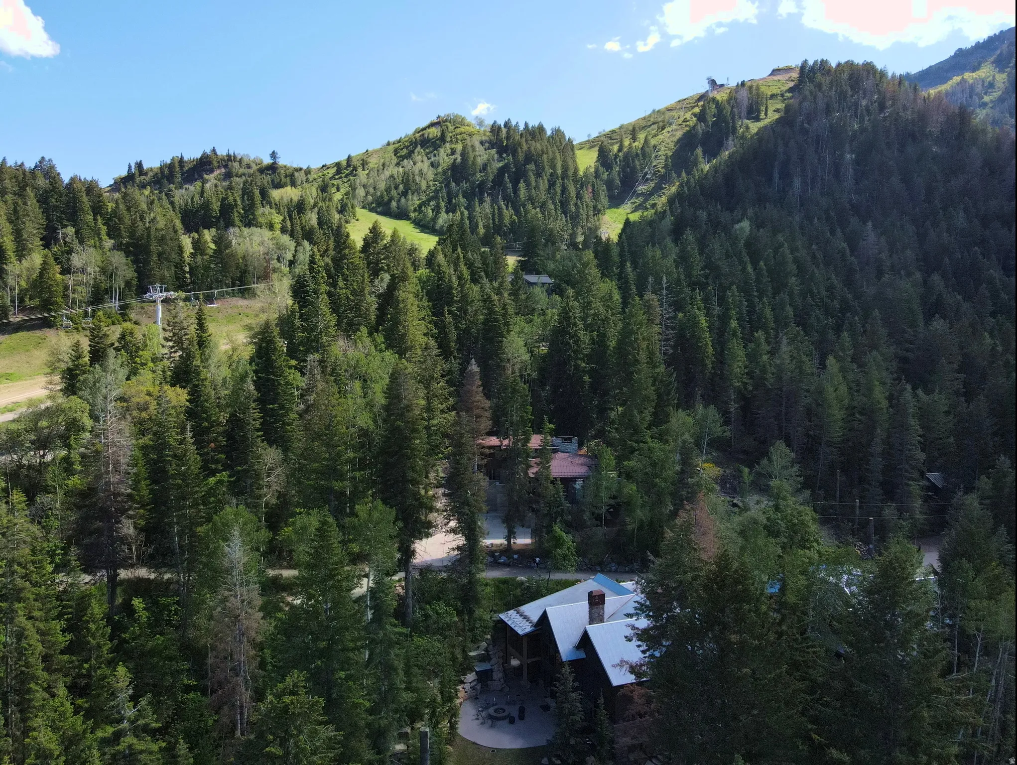 Mountain-side property featuring a multi-level structure with dark siding and a light-colored roof