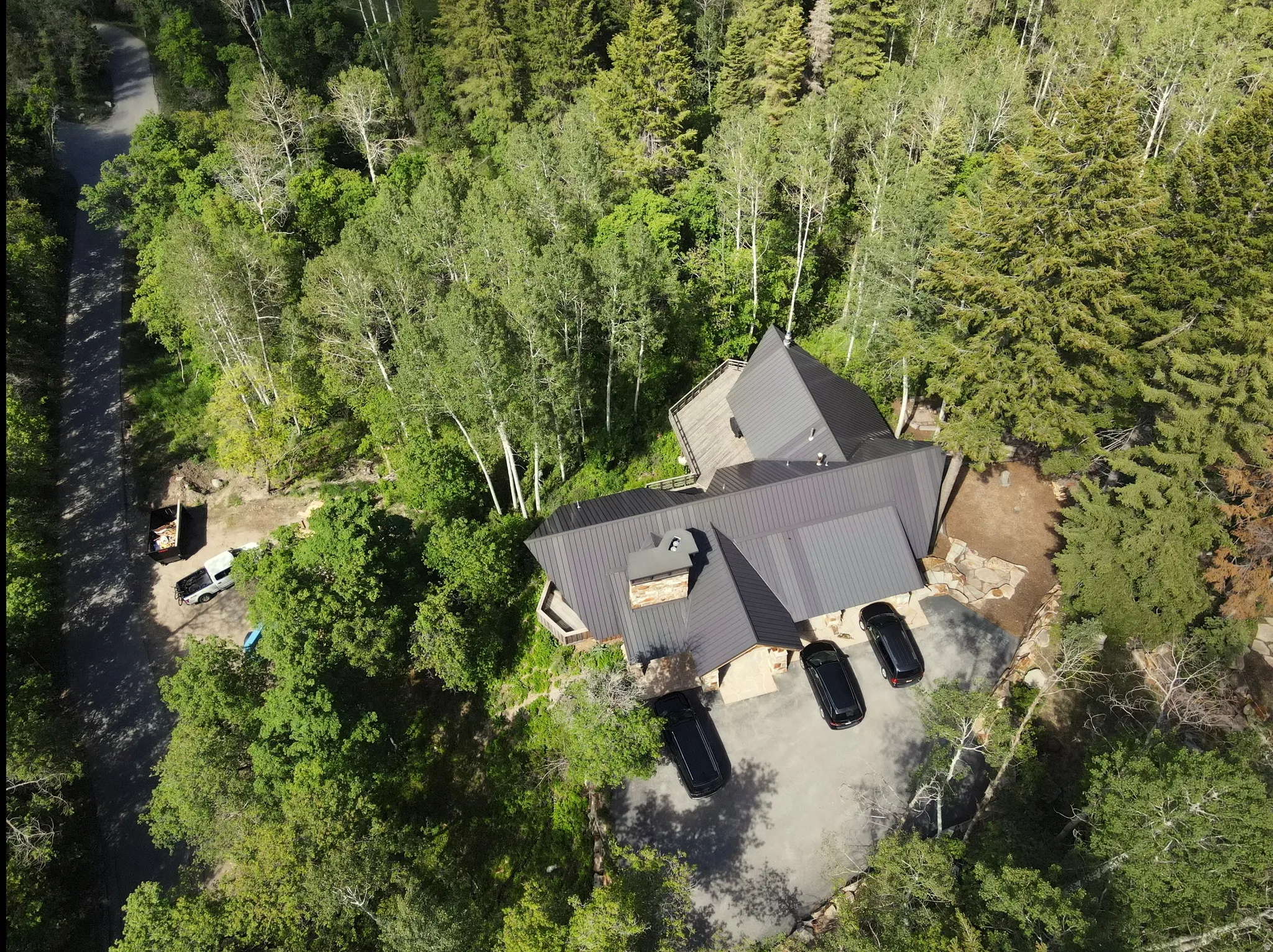 Contemporary residence featuring a dark metal roof, stone accents, and an expansive paved driveway