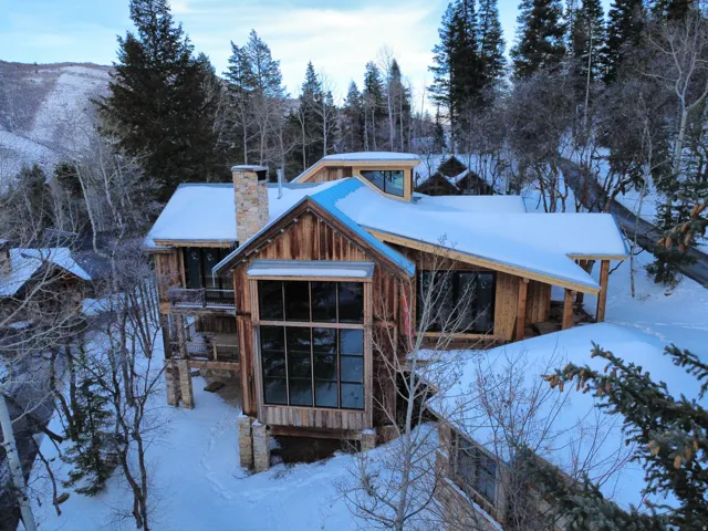 Snow covered back of property with a chimney and board and batten siding