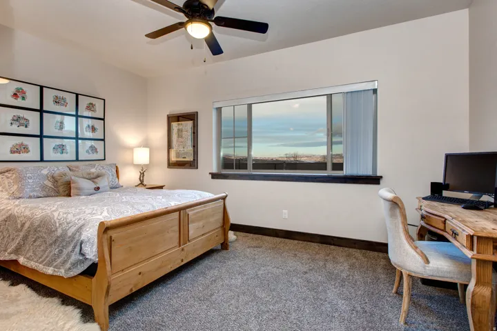 Carpeted bedroom with ceiling fan and a desk