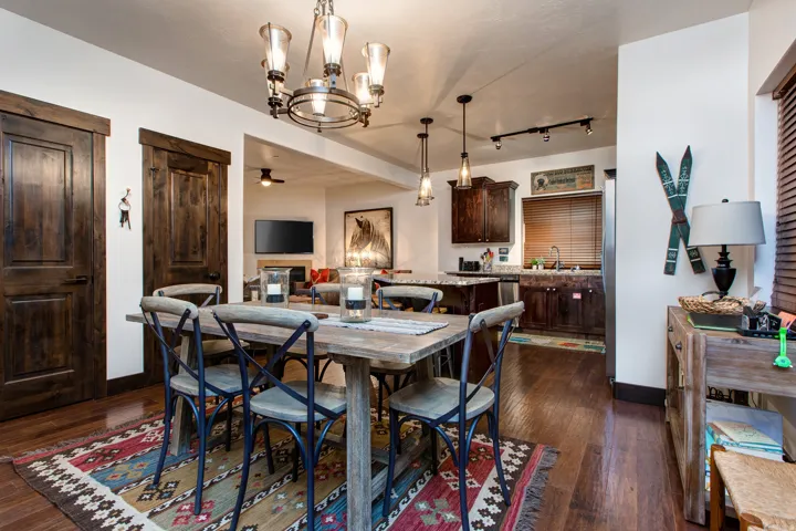 Dining area featuring ceiling fan, suspended lighting, and dark wood-type flooring