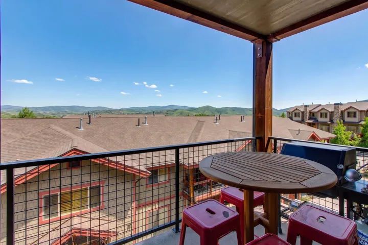 Private balcony with metal grid railing and wood-tone structural columns, offering expansive mountain scenery