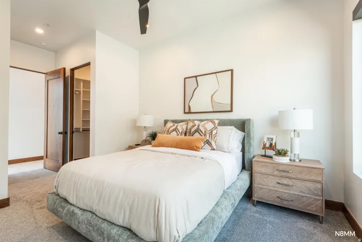 Guest bedroom with a walk-in closet, carpet floors, and a ceiling fan