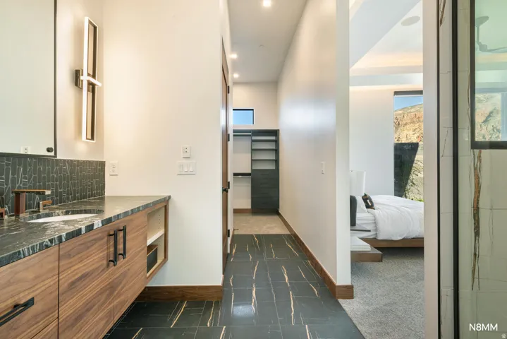 Primary full bathroom featuring vanity, ensuite bath, a walk-in closet, tasteful backsplash, and statement lighting
