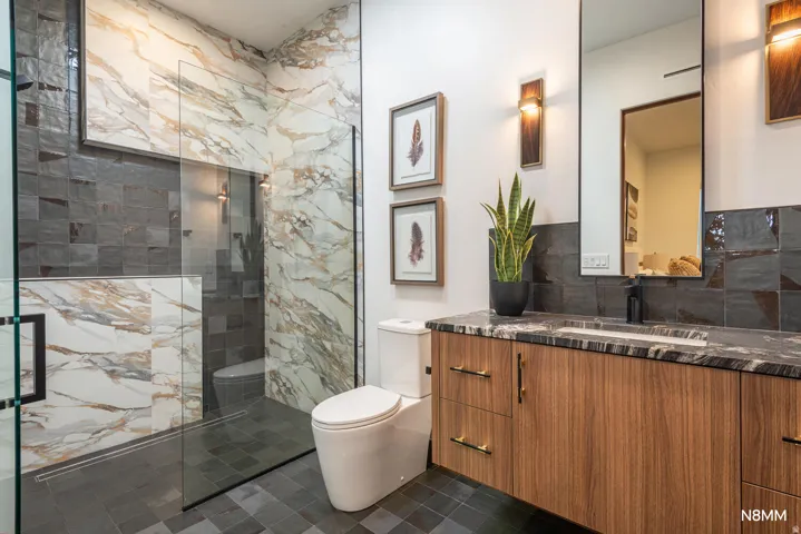 Full bathroom with a marble finish shower, vanity, and stone backsplash