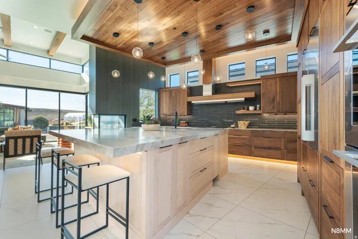 Kitchen featuring a spacious island, light stone counters, modern cabinets, and a high wood beamed ceiling