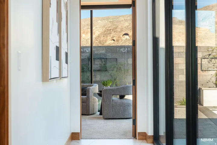 Hallway to primary bedroom featuring plenty of natural light from the sliders to the pool area.