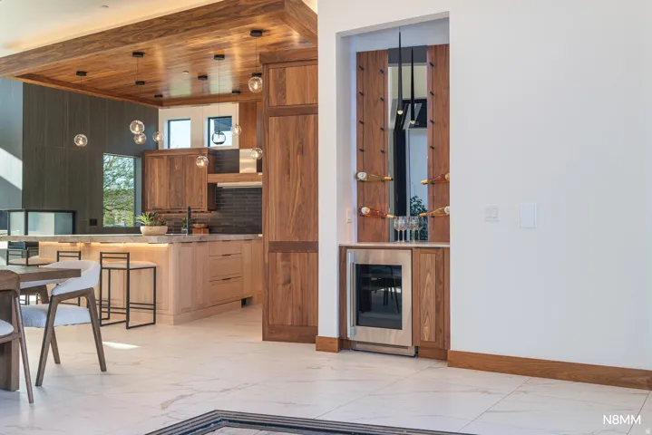 Kitchen featuring beverage cooler, open shelves, a kitchen breakfast bar, light flooring, and wood finish cabinets.