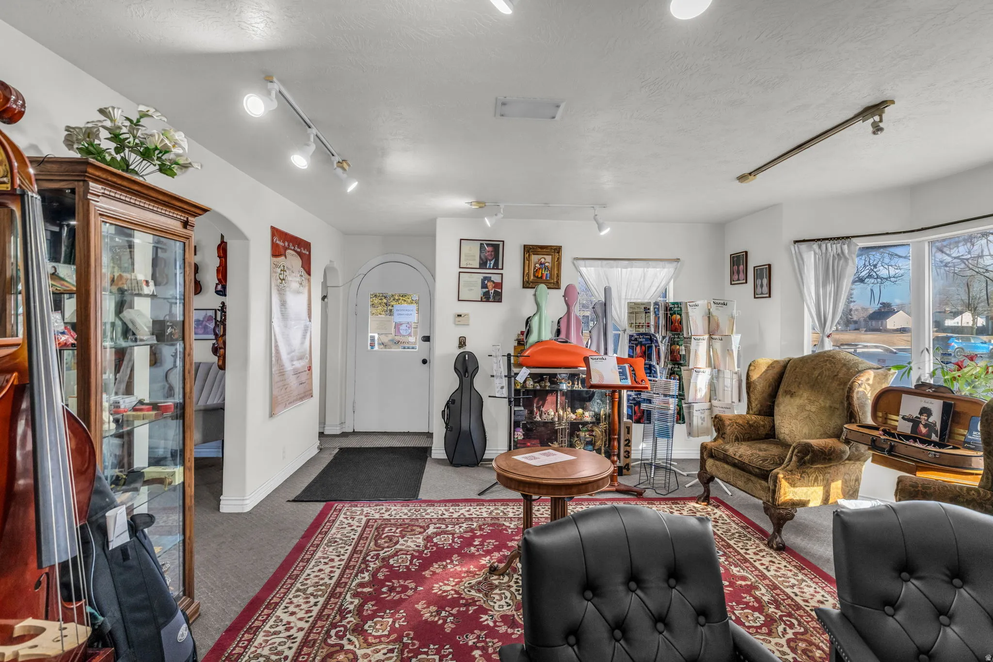 Carpeted living room with rail lighting, arched walkways, and a textured ceiling