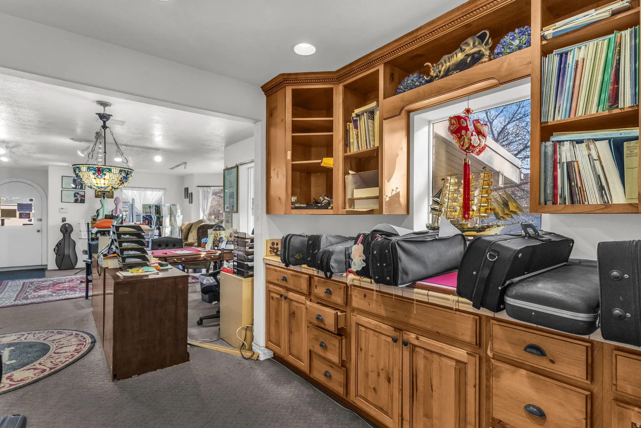 Kitchen featuring wood finish cabinets, open floor plan, carpet floors, hanging light fixtures, and open shelves