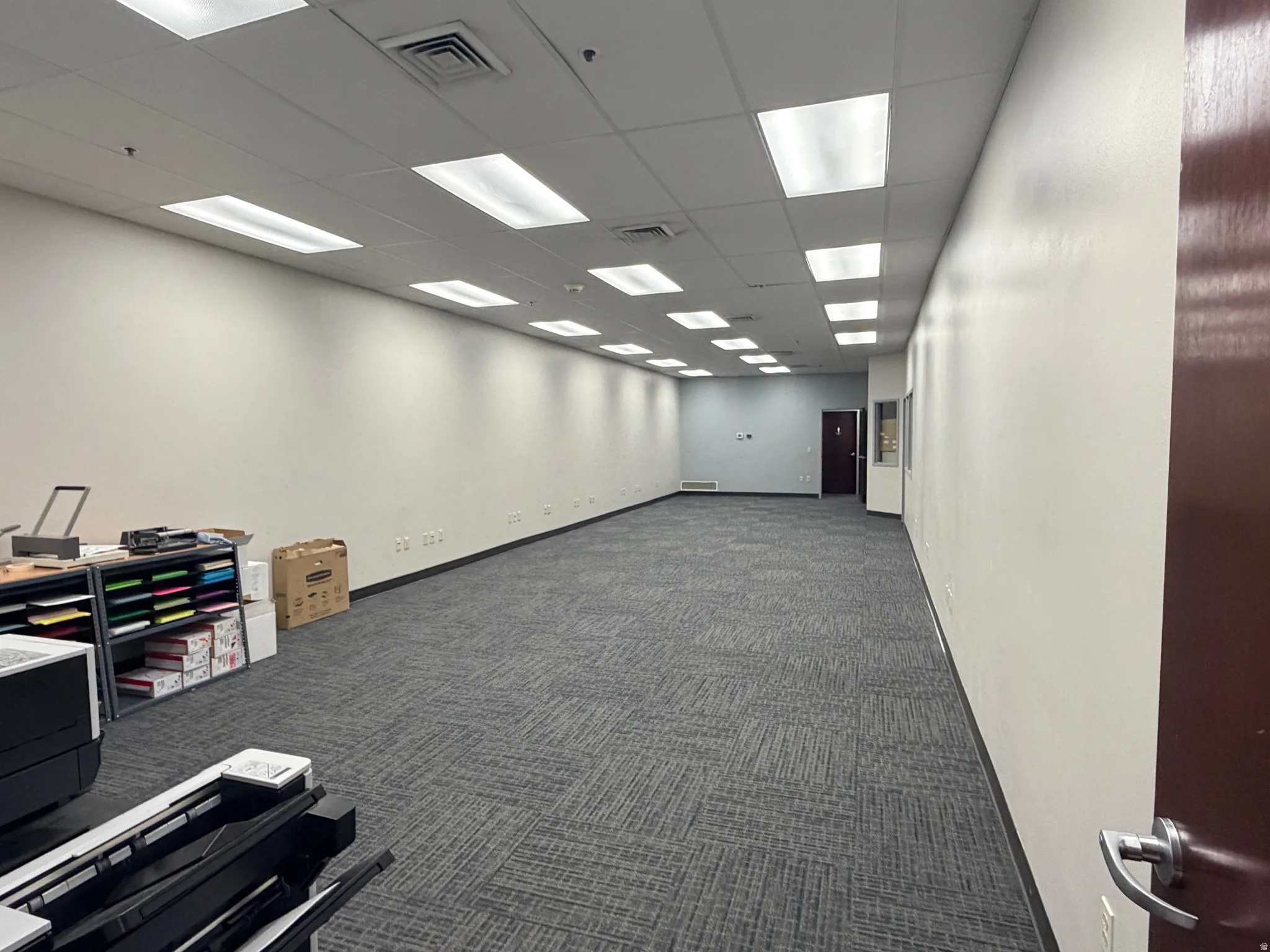 Unfurnished room featuring a drop ceiling and dark carpet