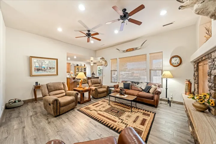 Living area with light wood-type flooring, a ceiling fan, recessed lighting, and a fireplace