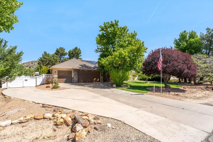 View of front of property featuring driveway, stone siding, a garage, a tile roof, and a gate