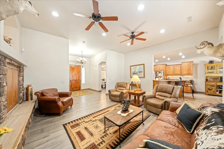 Living room with arched walkways, light wood-style floors, a ceiling fan, and suspended lighting
