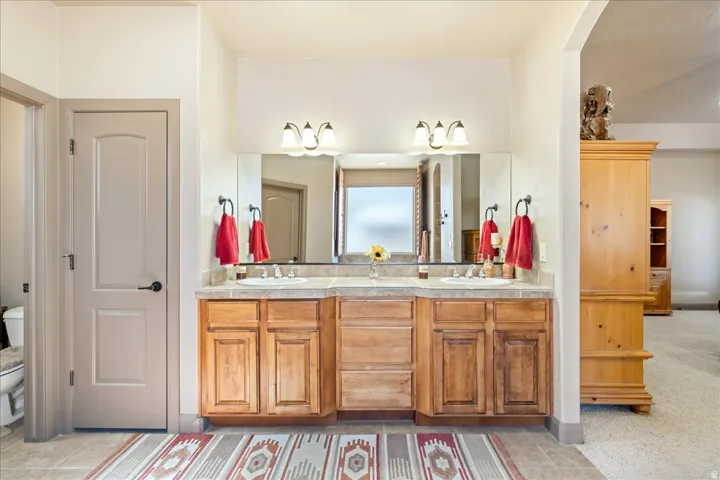 Full bath with double vanity and light colored carpet