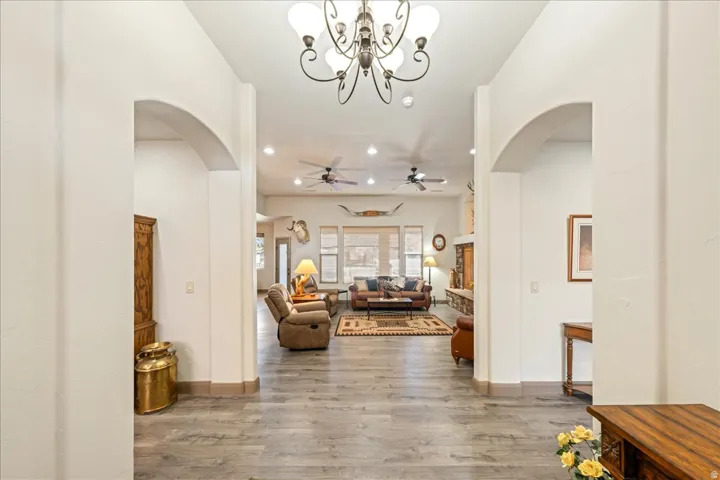 Foyer featuring arched walkways, light wood finished floors, suspended lighting, and ceiling fan