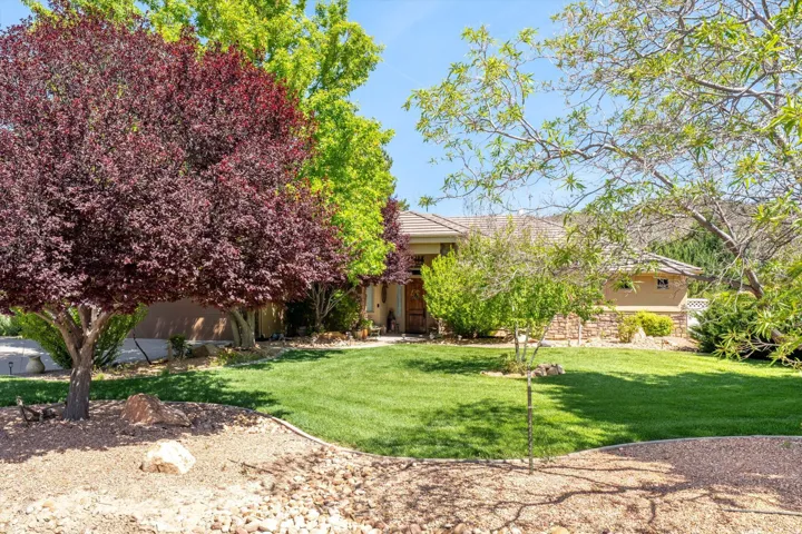 View of property hidden behind natural elements featuring stucco siding, a front yard, and a tiled roof