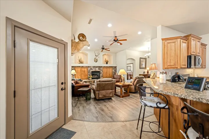 Kitchen featuring a kitchen breakfast bar, light stone countertops, arched walkways, a chandelier, and stainless steel microwave