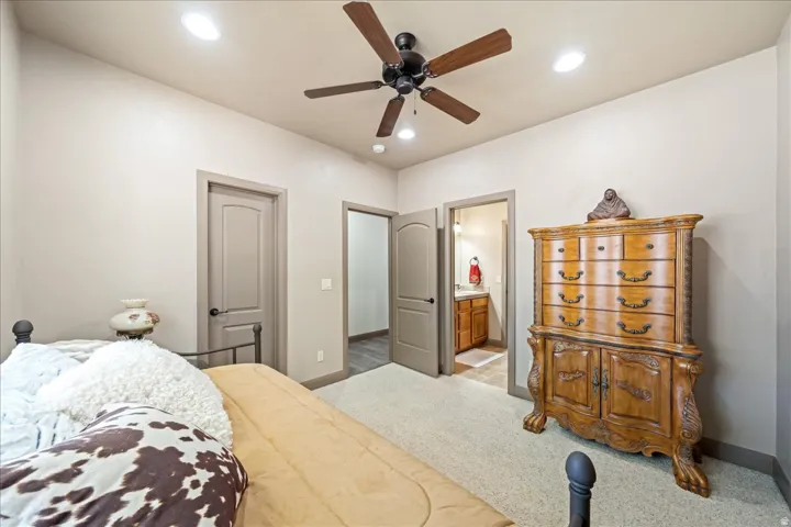 Carpeted bedroom featuring ceiling fan, ensuite bathroom, and recessed lighting