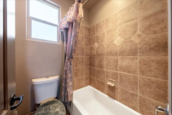 Full bath featuring toilet and shower / bathtub combination with curtain