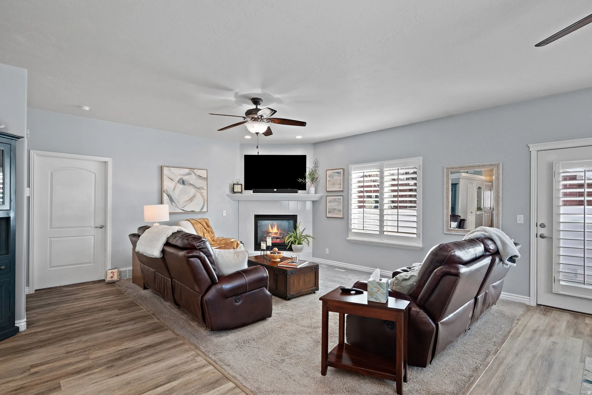 Living room with a ceiling fan, a glass covered fireplace, and light wood-type flooring