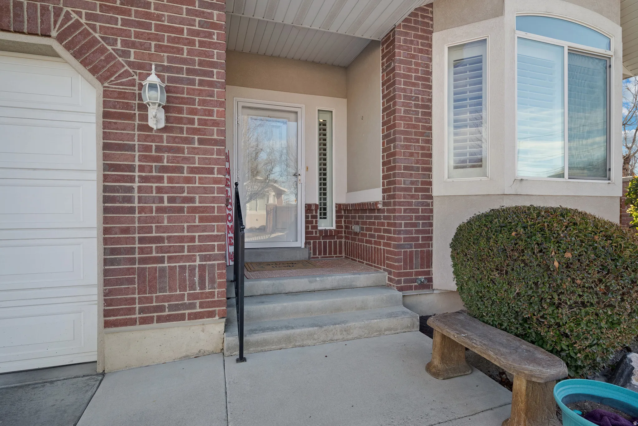 Property entrance with brick siding, a garage, and stucco siding