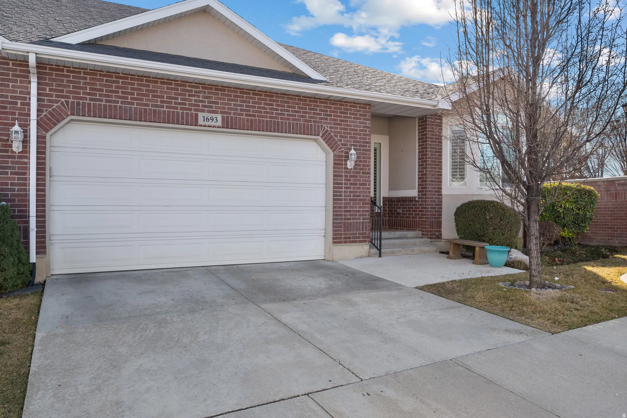 Ranch-style home featuring brick siding, concrete driveway, a garage, and roof with shingles