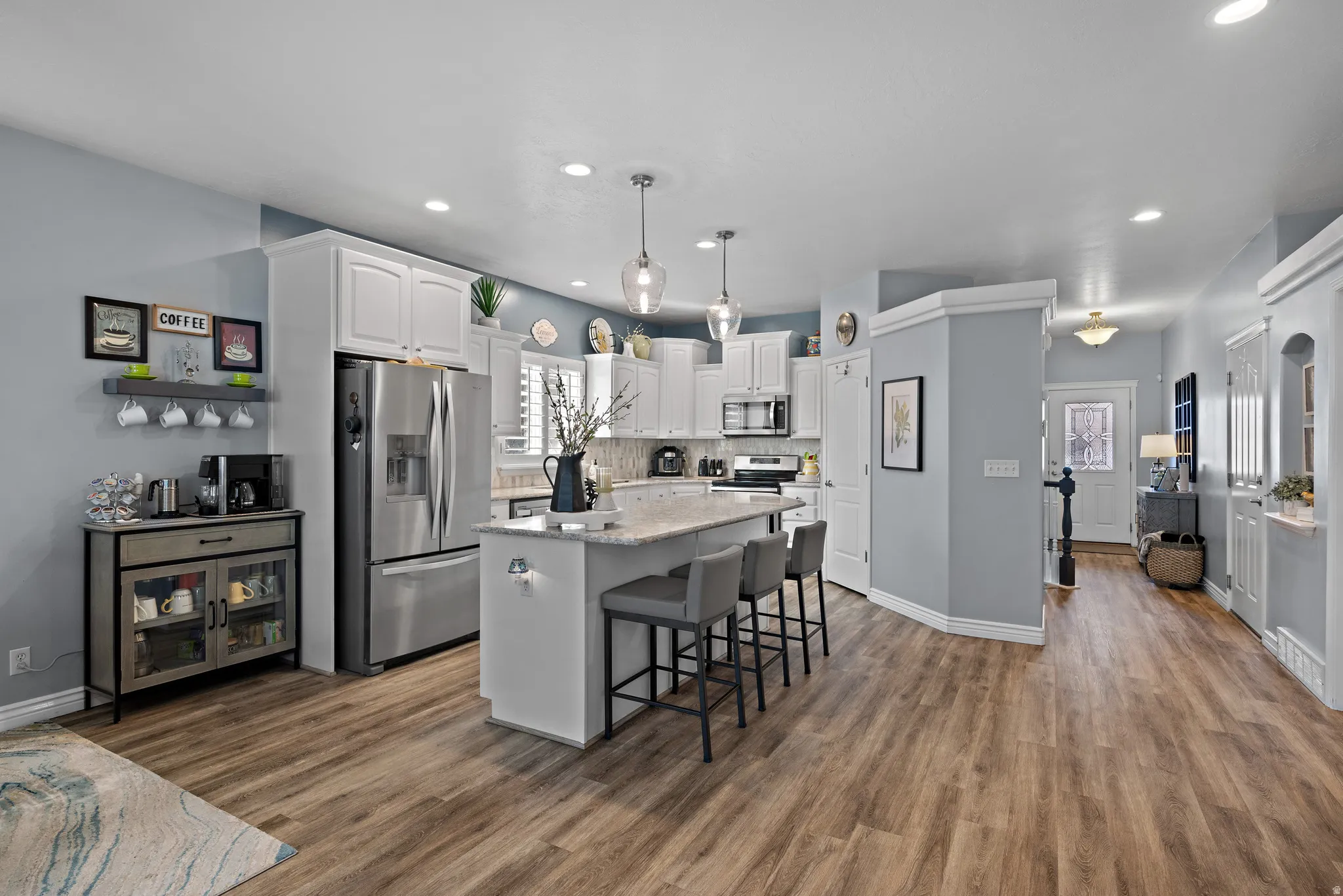 Kitchen with white cabinetry, a kitchen breakfast bar, a kitchen island, stainless steel appliances, and light stone countertops