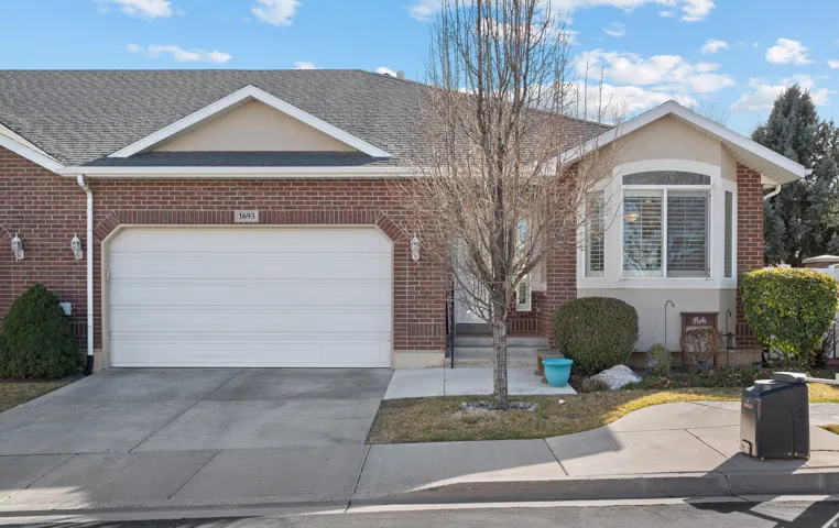 Ranch-style home with brick siding, concrete driveway, an attached garage, and stucco siding