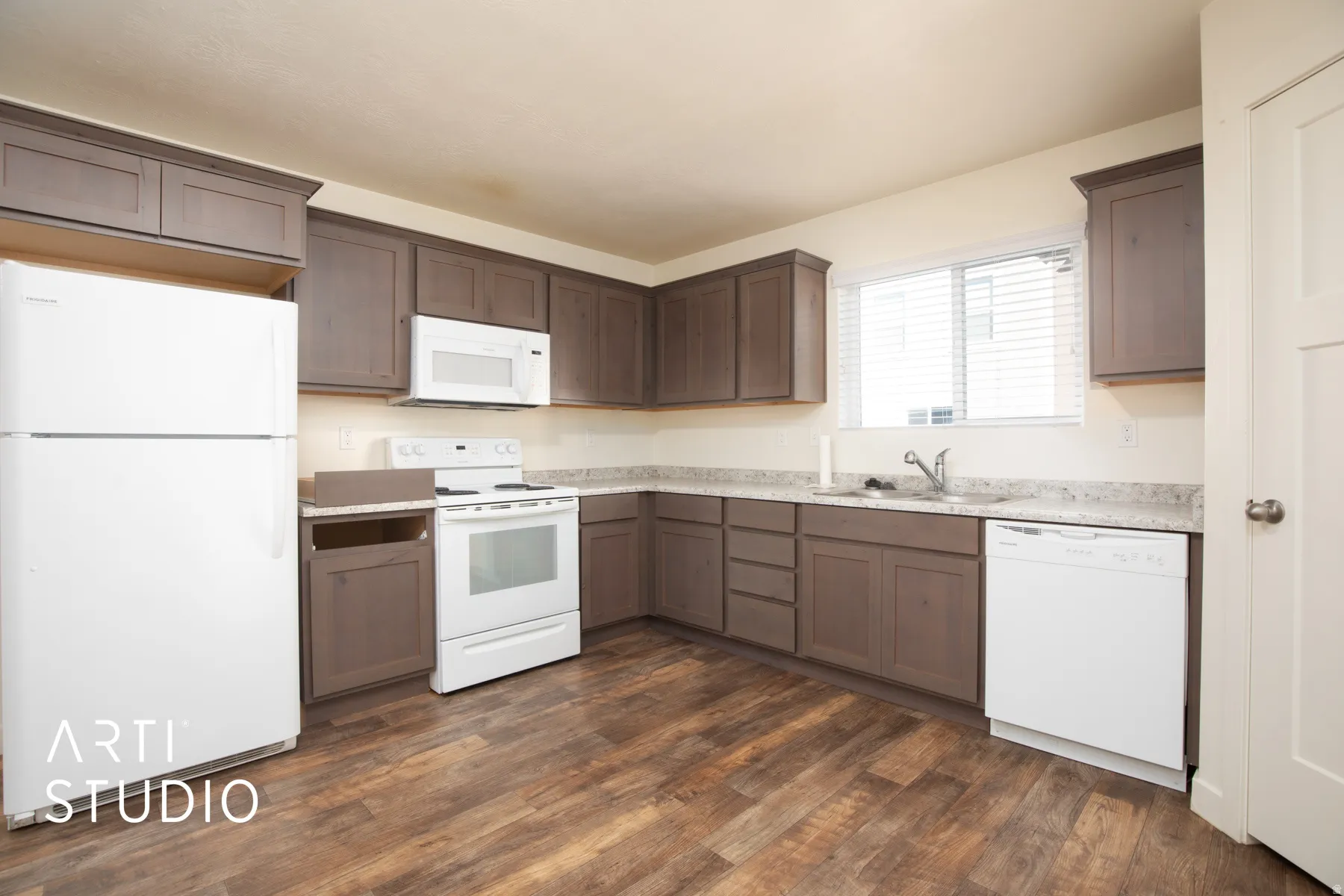 Kitchen featuring white appliances, light countertops, dark wood finished floors, and dark wood finish cabinets