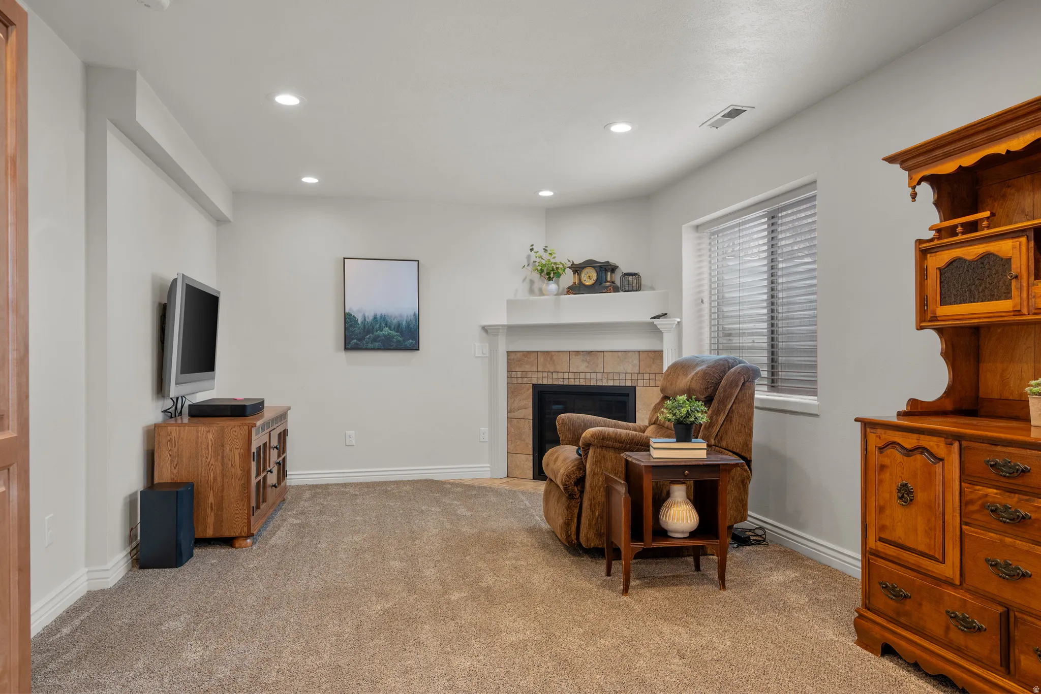 Sitting room with a tiled fireplace, light carpet, and recessed lighting
