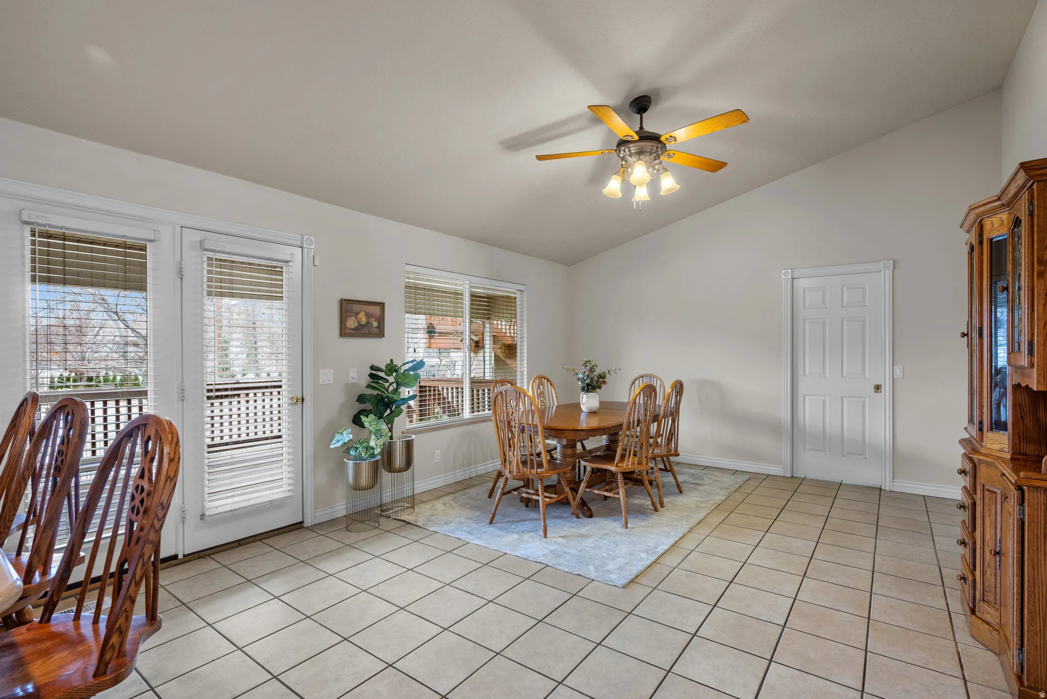 Dining area with a ceiling fan, light tile patterned flooring, and vaulted ceiling