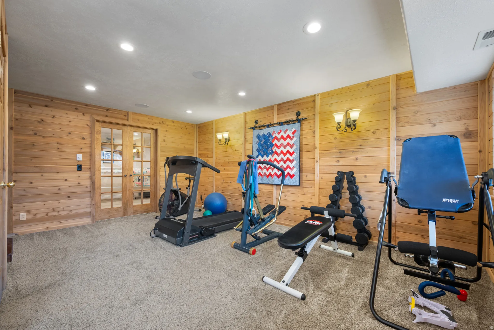 Exercise room with carpet flooring, recessed lighting, wooden walls, and french doors