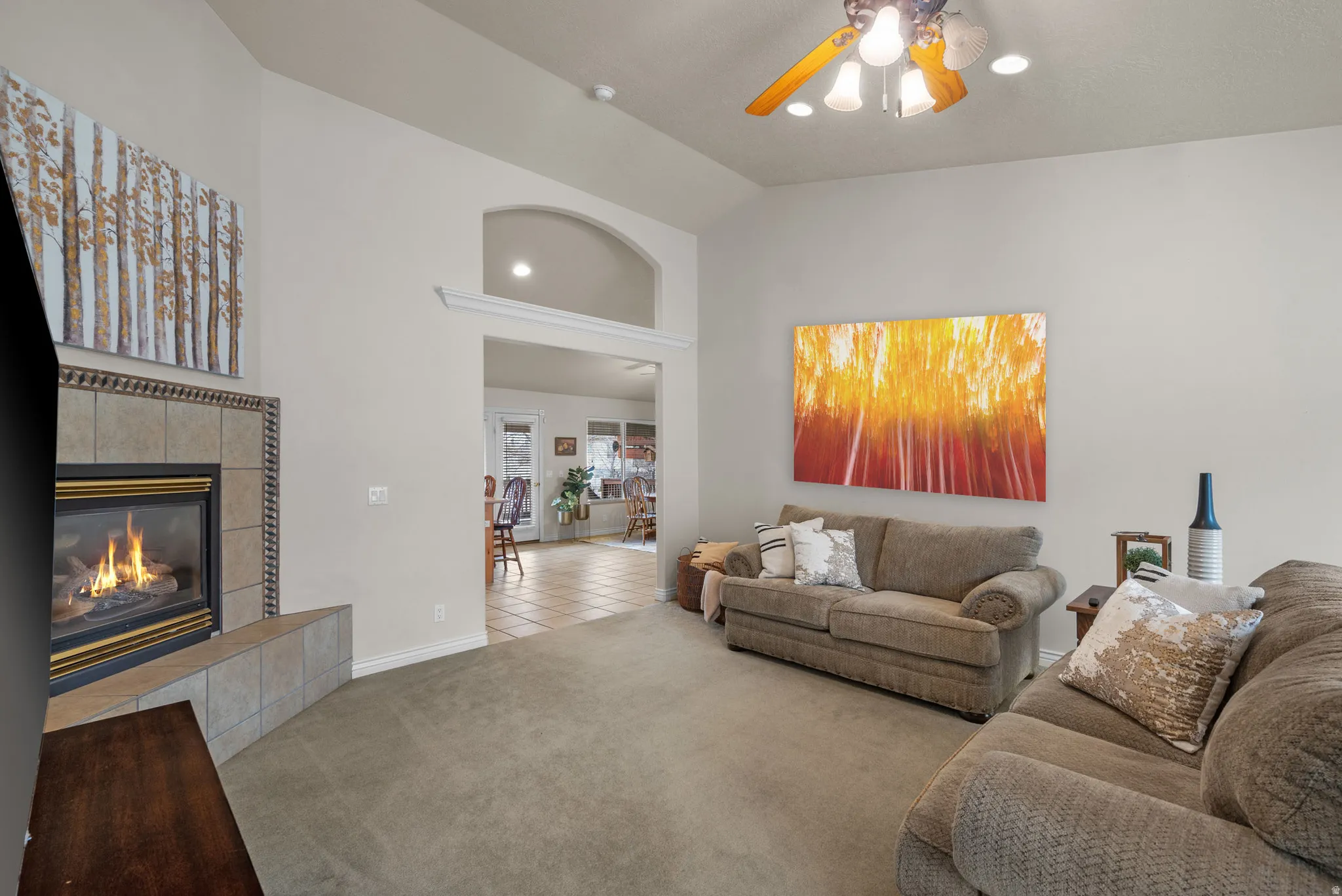 Living area with a tile fireplace, a ceiling fan, recessed lighting, vaulted ceiling