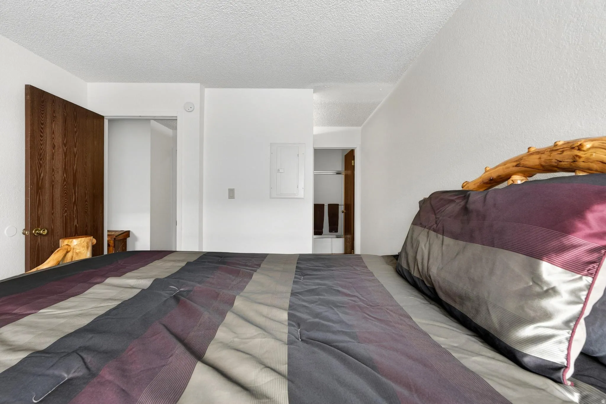 Bedroom featuring a textured ceiling, electric panel, and a closet