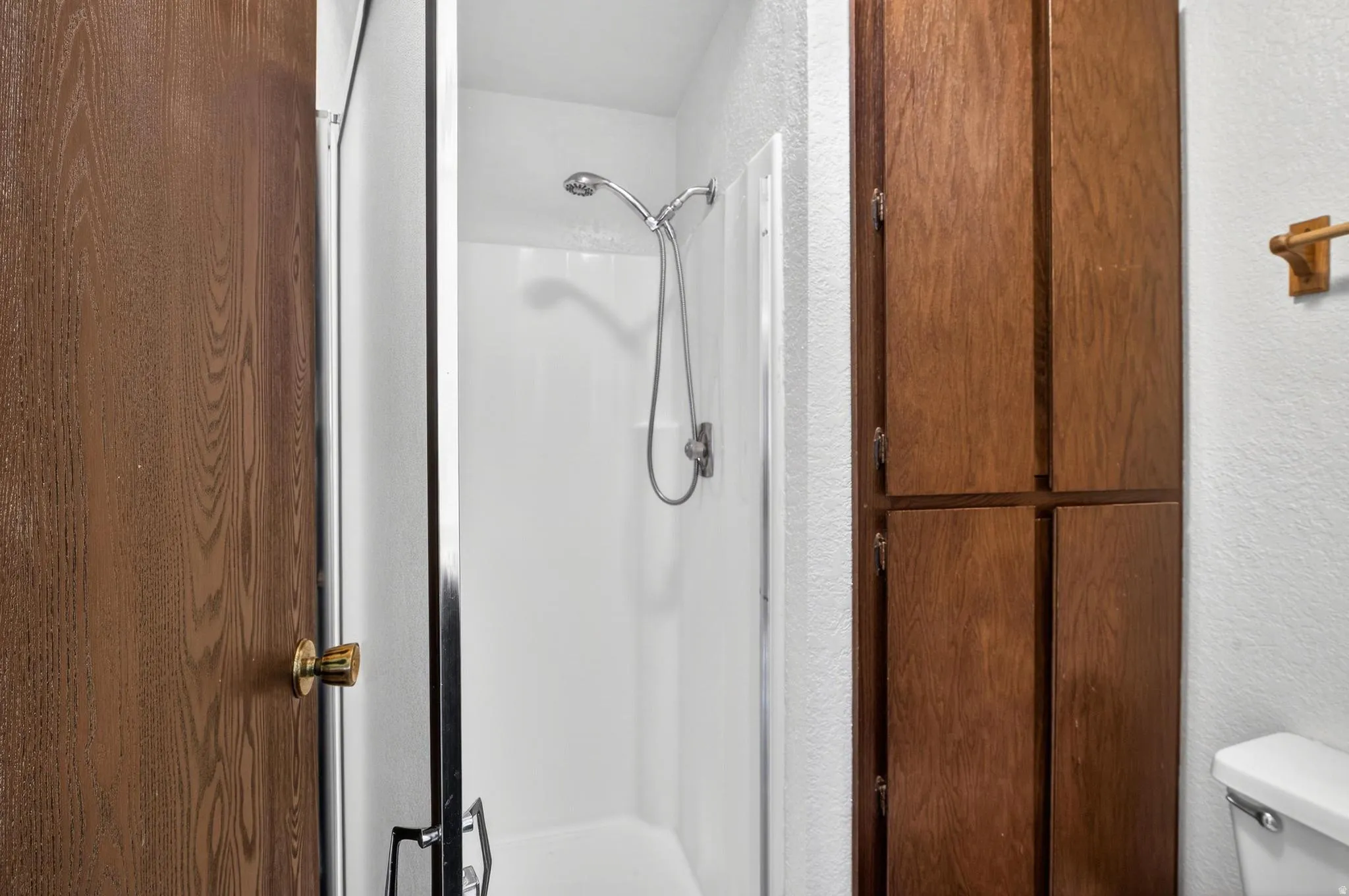Full bathroom featuring a textured wall and a stall shower