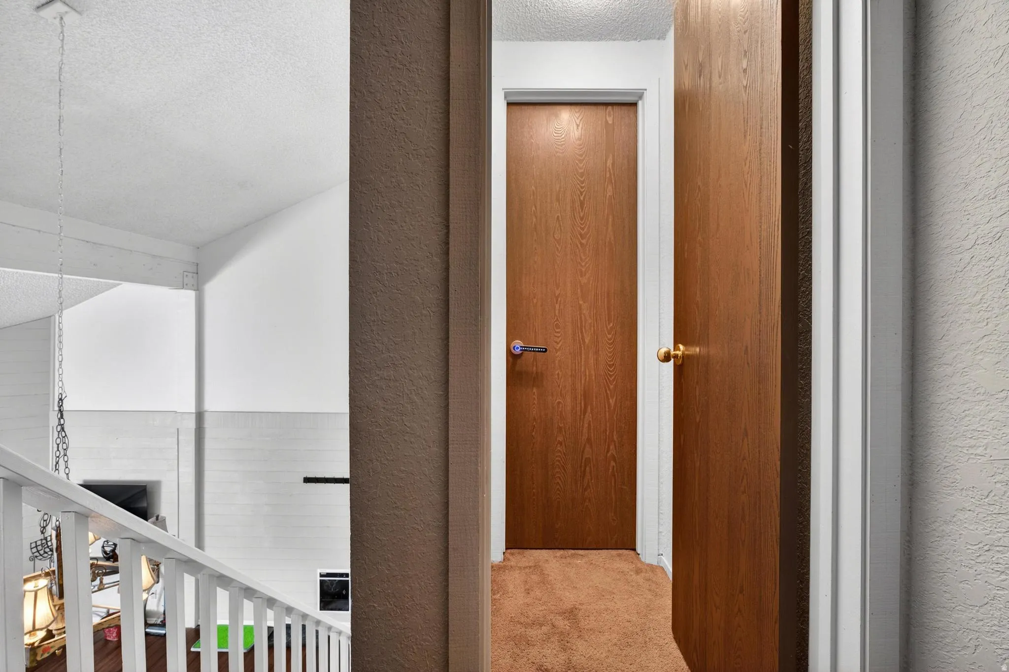 Hall with a textured ceiling, a textured wall, and carpet floors