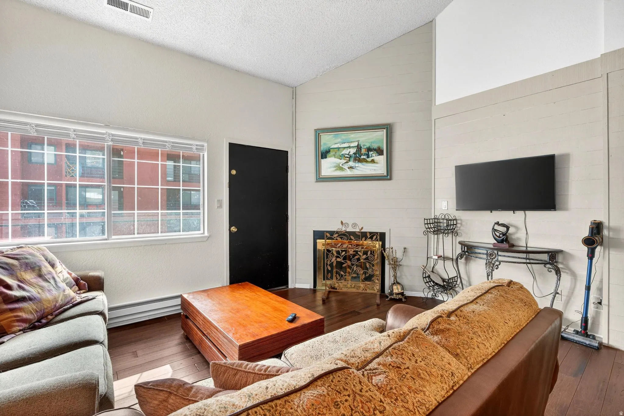Living room with dark wood-type flooring, a fireplace, and a baseboard heating unit