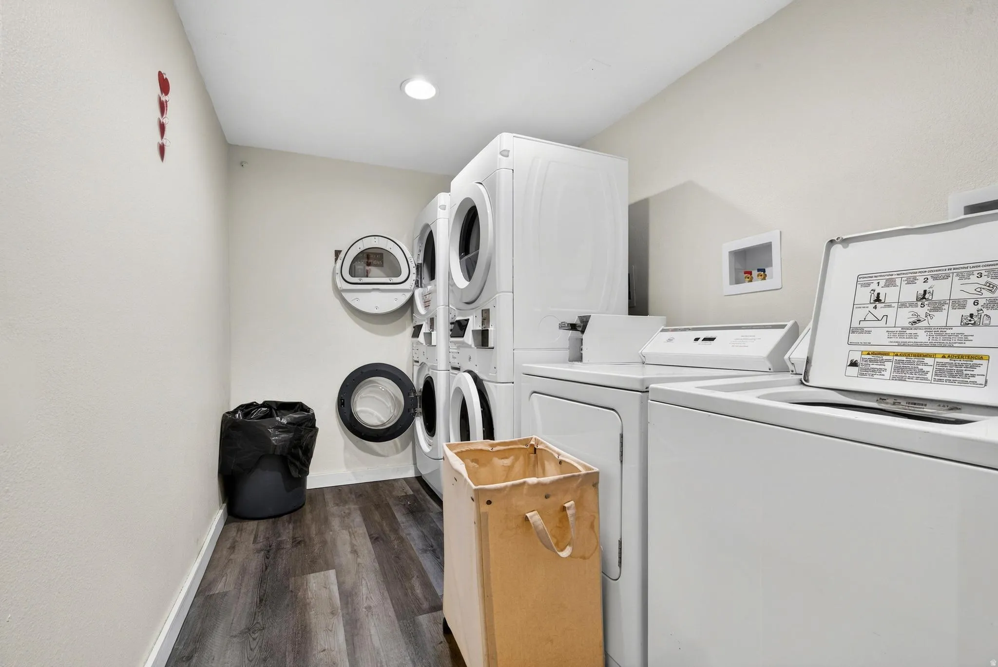 Shared laundry room featuring dark wood finished floors and stacked washer / dryer