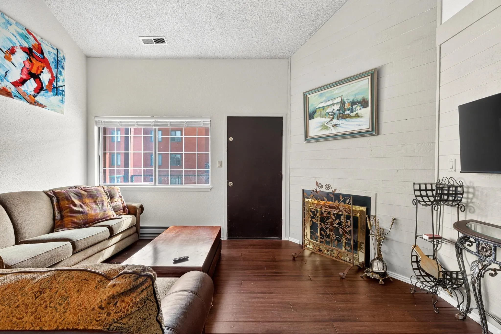 Living room featuring a fireplace, dark wood finished floors, a textured ceiling, and a baseboard radiator