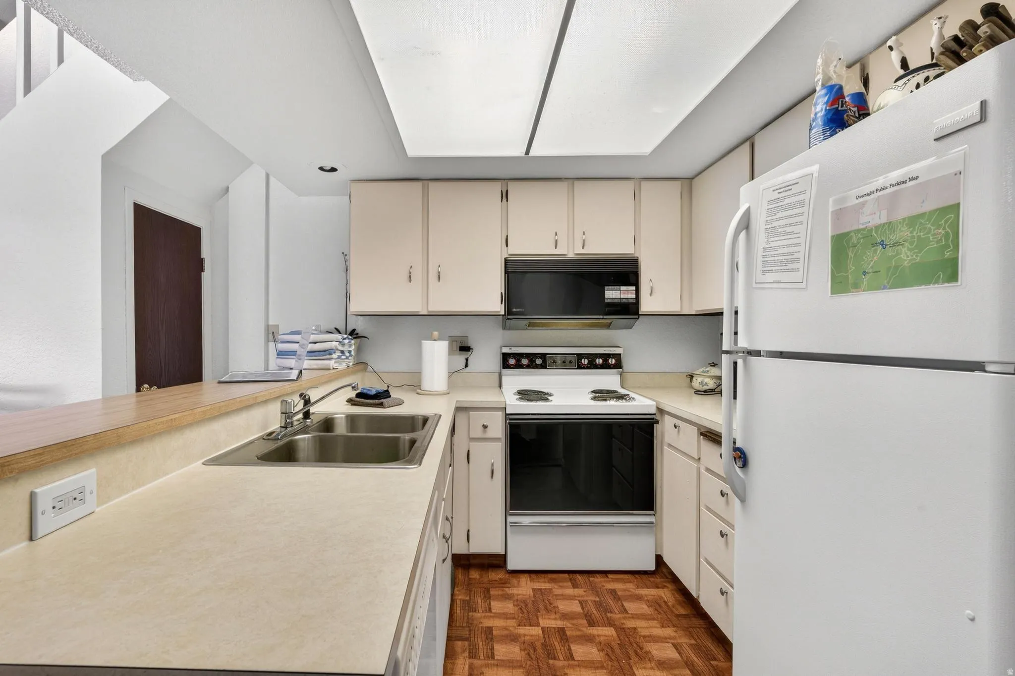 Kitchen featuring white appliances, light countertops, cream cabinets, parquet floors, and a peninsula
