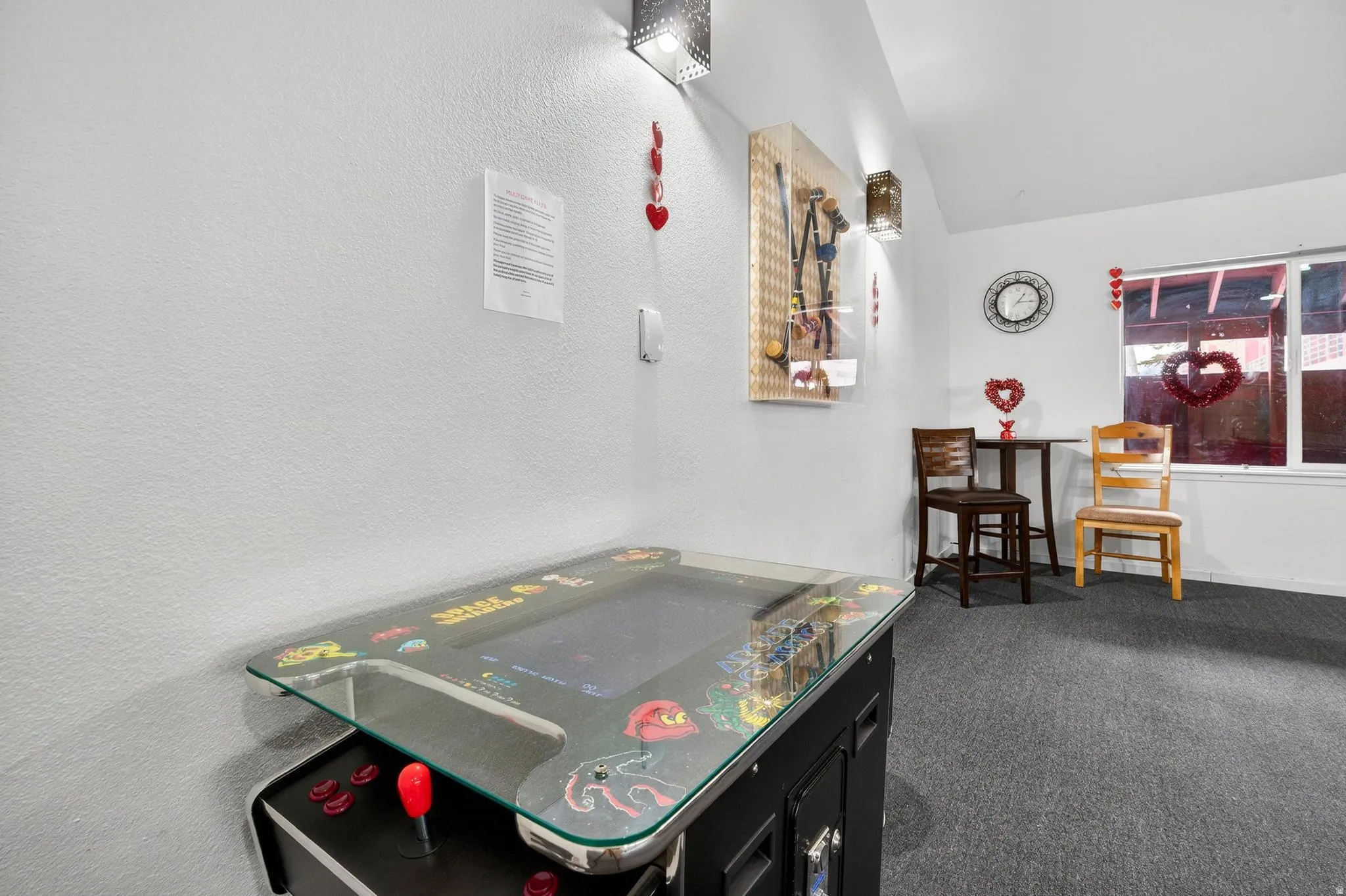 Game room featuring lofted ceiling, dark colored carpet, and a textured wall