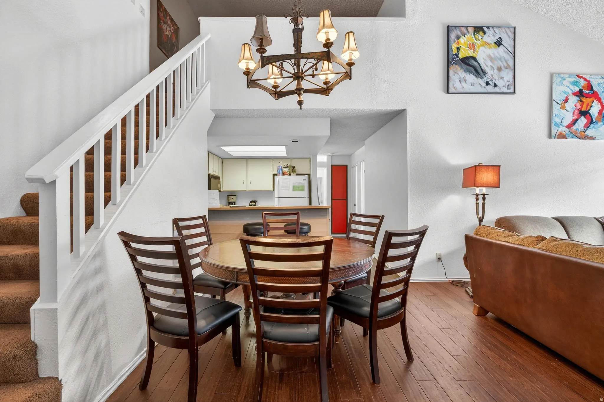 Dining area with dark wood-style floors, a chandelier, and a textured wall