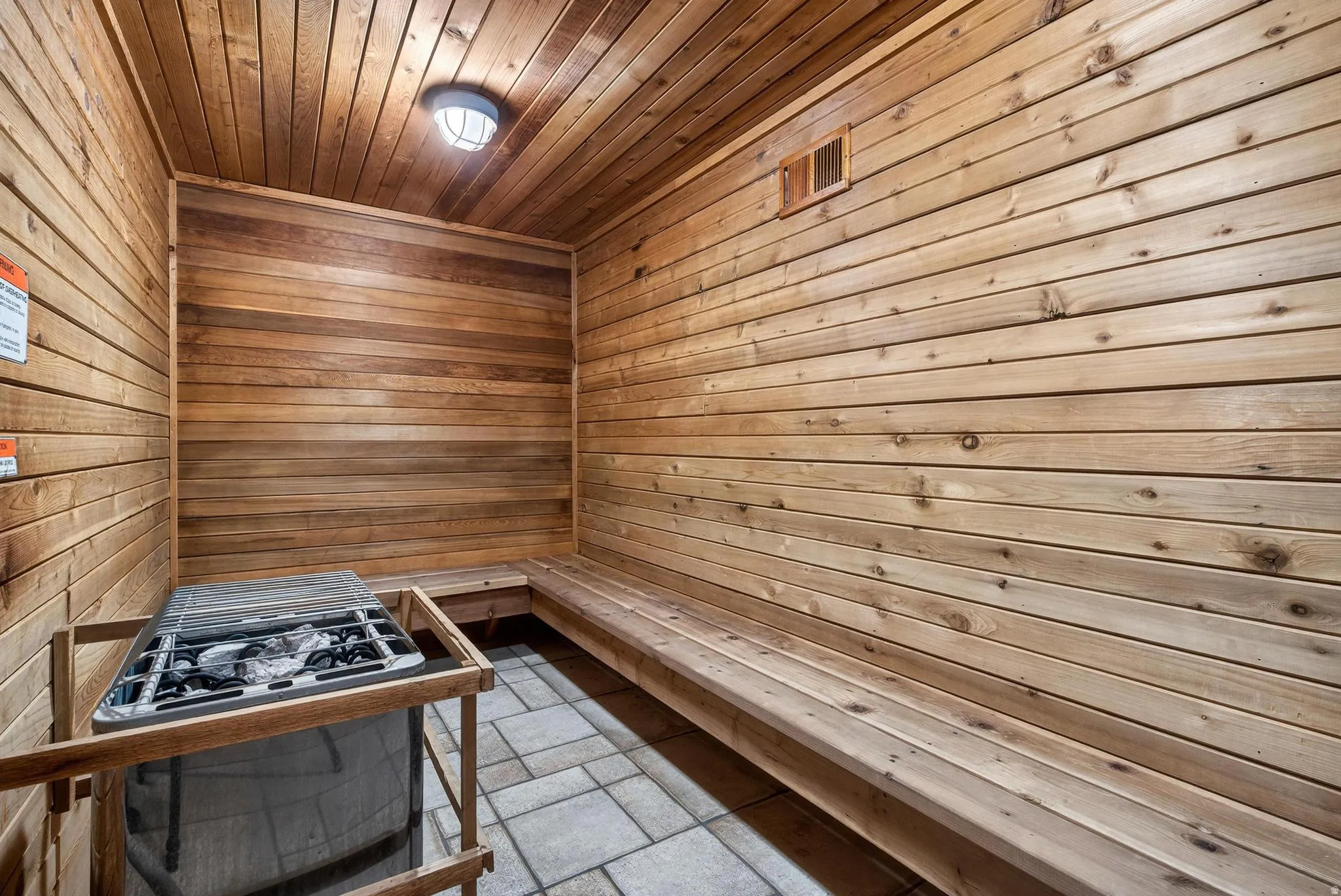 Sauna / steam room with wooden walls, wooden ceiling, and stone tile flooring
