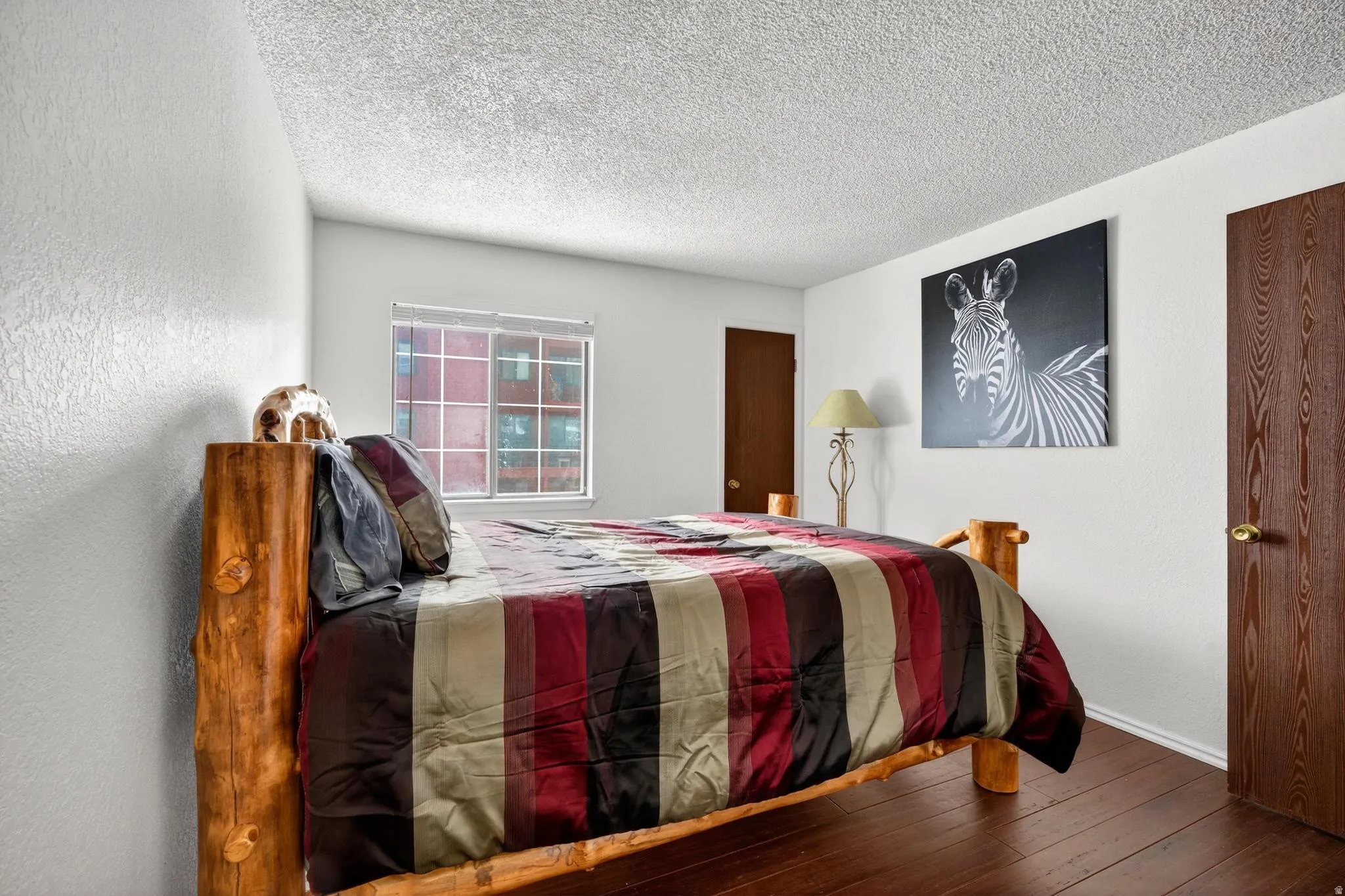 Bedroom featuring a textured ceiling, hardwood / wood-style floors, and a textured wall