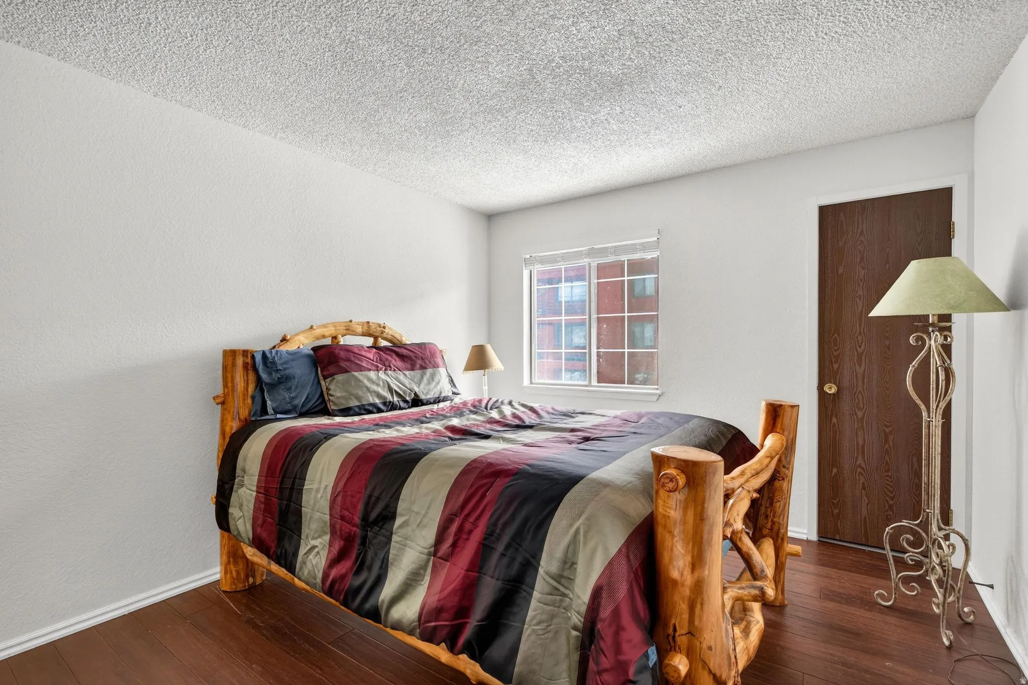 Bedroom featuring wood-type flooring, a textured ceiling, and a textured wall
