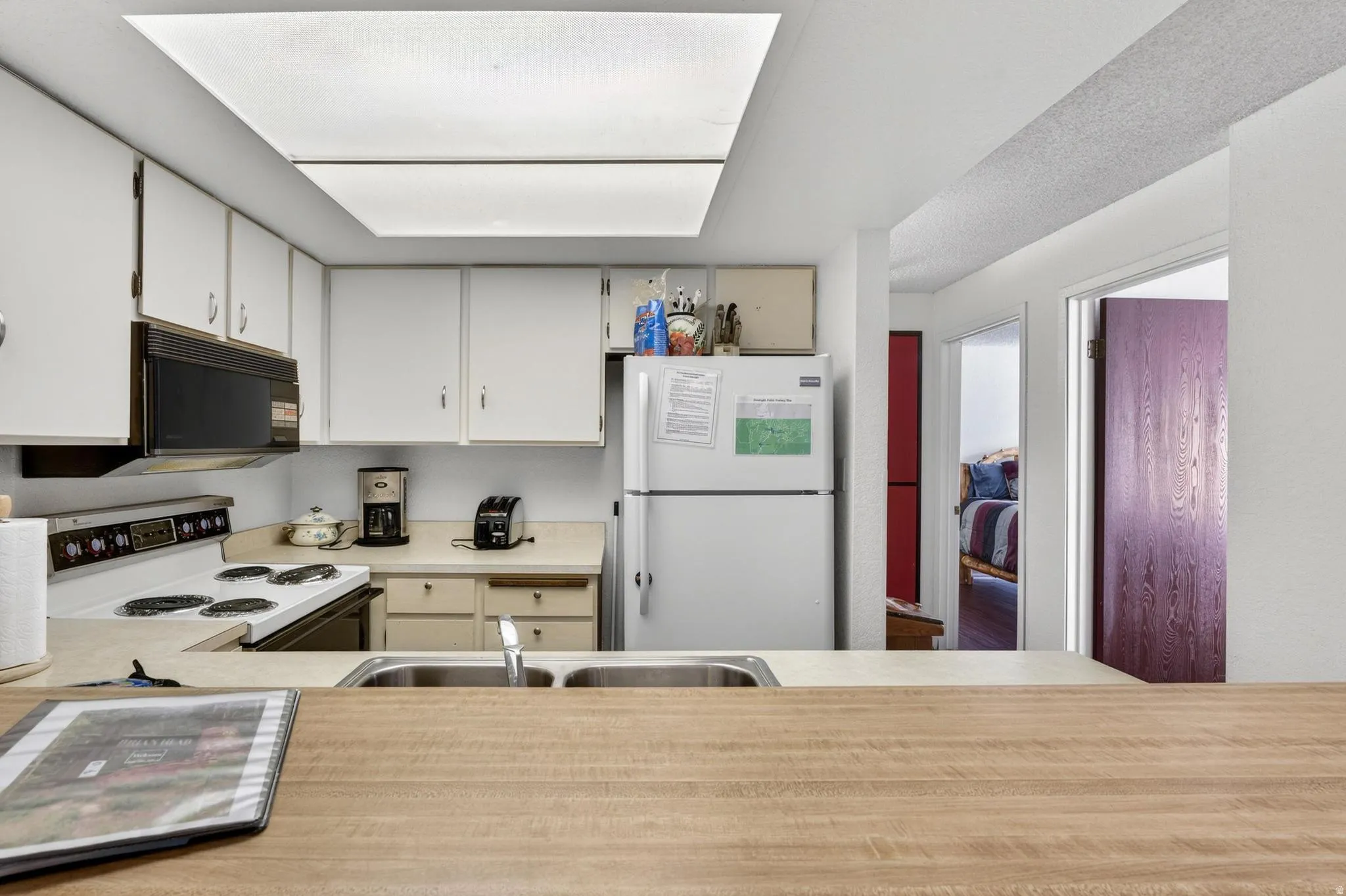Kitchen with light countertops, white appliances, and white cabinets