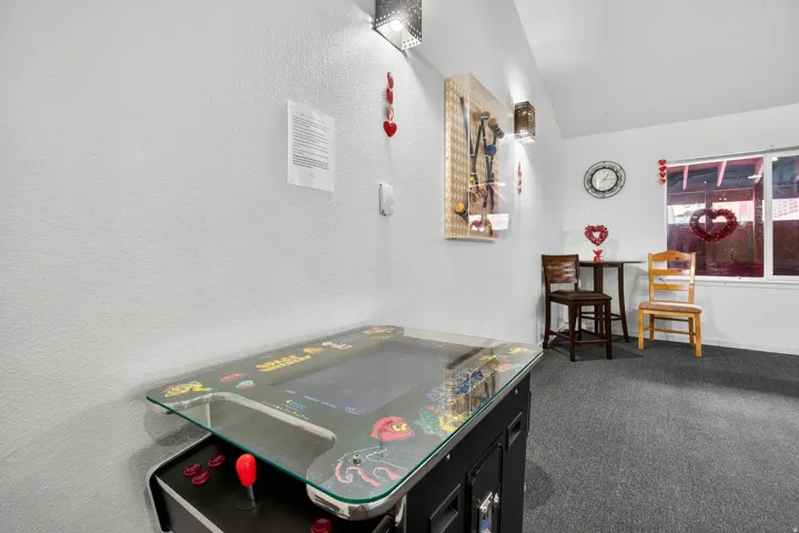 Game room featuring lofted ceiling, dark colored carpet, and a textured wall