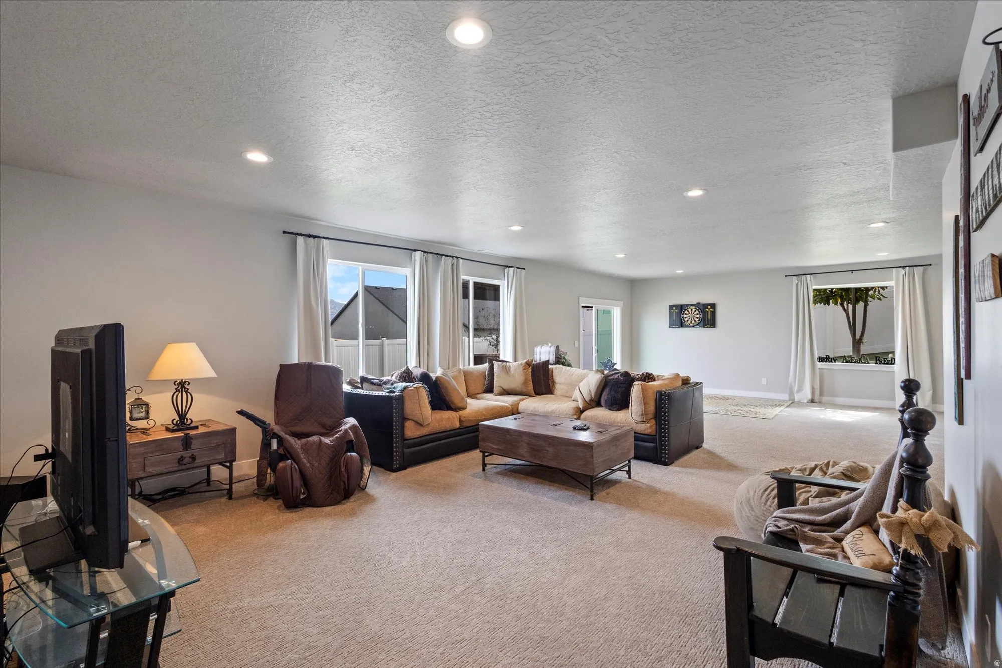 Living room with light colored carpet, a textured ceiling, and recessed lighting