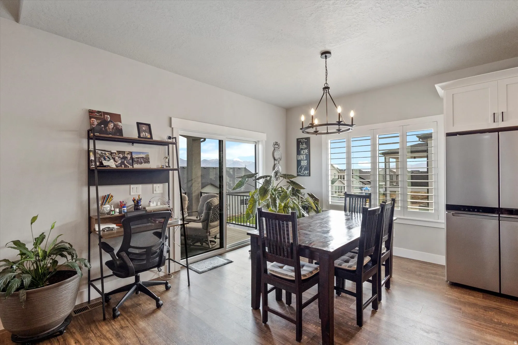 Dining area with dark wood finished floors, a desk, a chandelier, and a textured ceiling